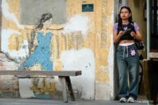 street art girl watching real girl holding a smartphone